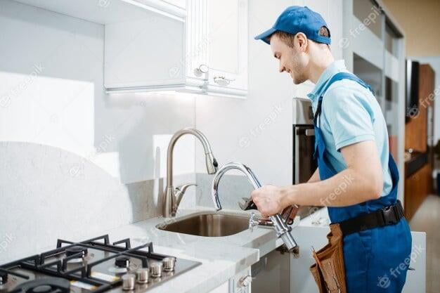 Cheerful plumber fixing faucet